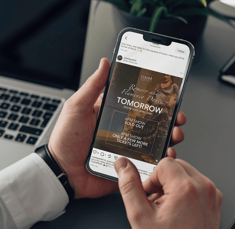 Person holding phone viewing a social media post for an upcoming event at Roost Restaurant