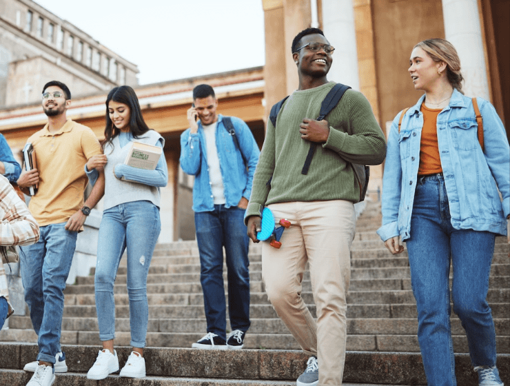 a group of diverse college students walking down a flight of stairs at their university