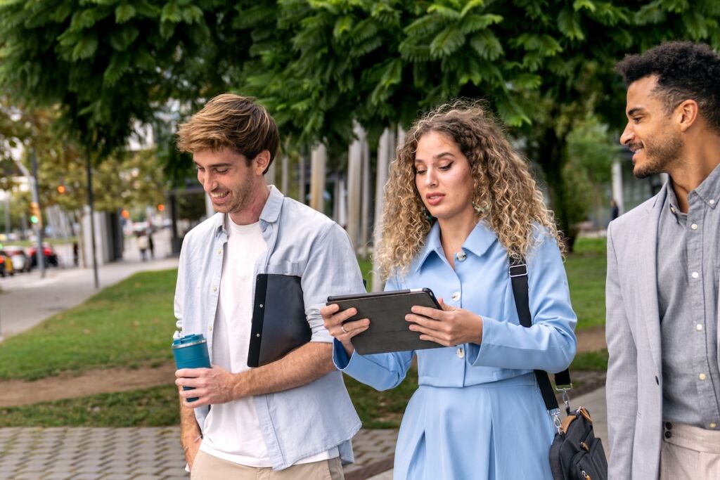 College students reviewing information on a tablet while walking across campus, illustrating digital engagement and higher education marketing strategies for prospective students.